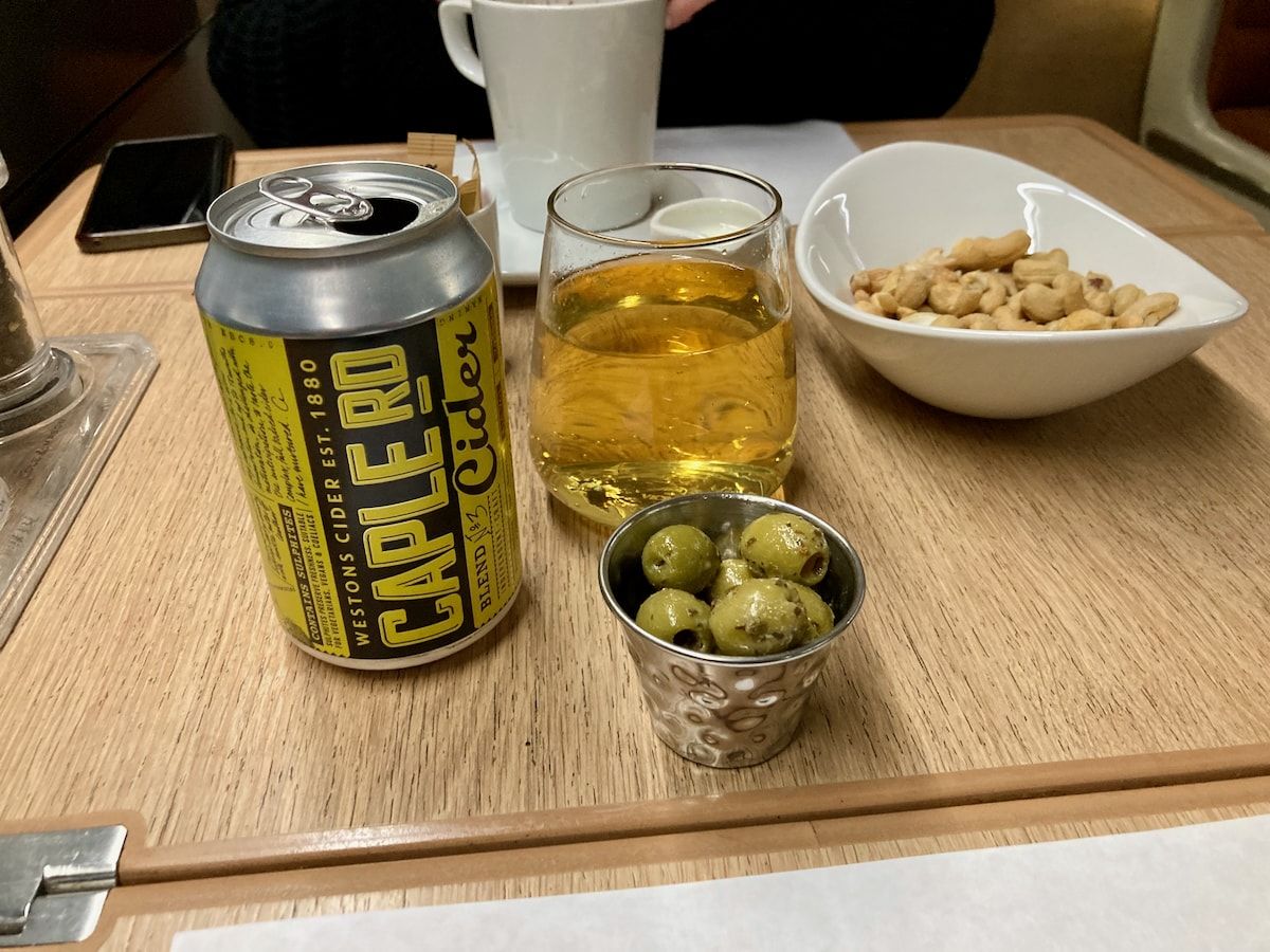 Eine Dose Cider, ein Glas, eine Tasse, Oliven und Cashew-Kerne