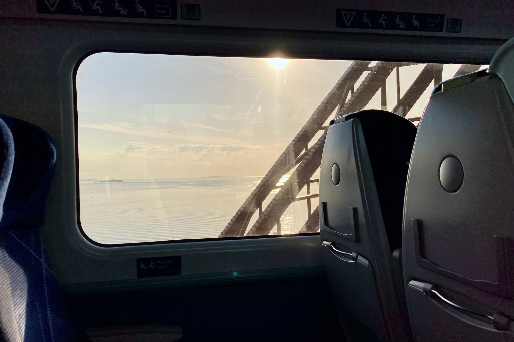Bild: Aussicht aus dem Zugfenster auf Meer mit einem Brückenpfeiler