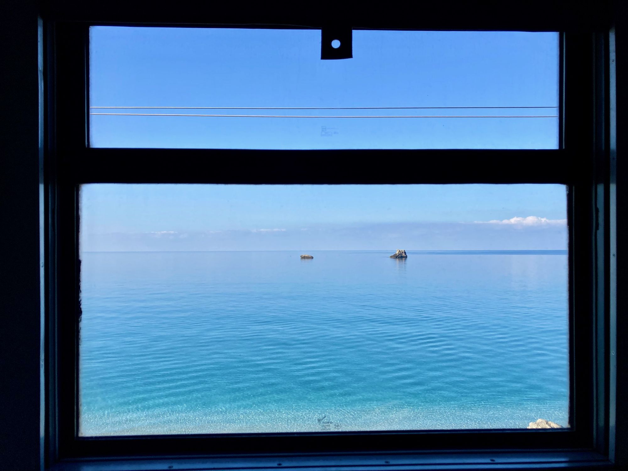 Ausblick aus dem Abteilfenster mit türkisblauem Meer