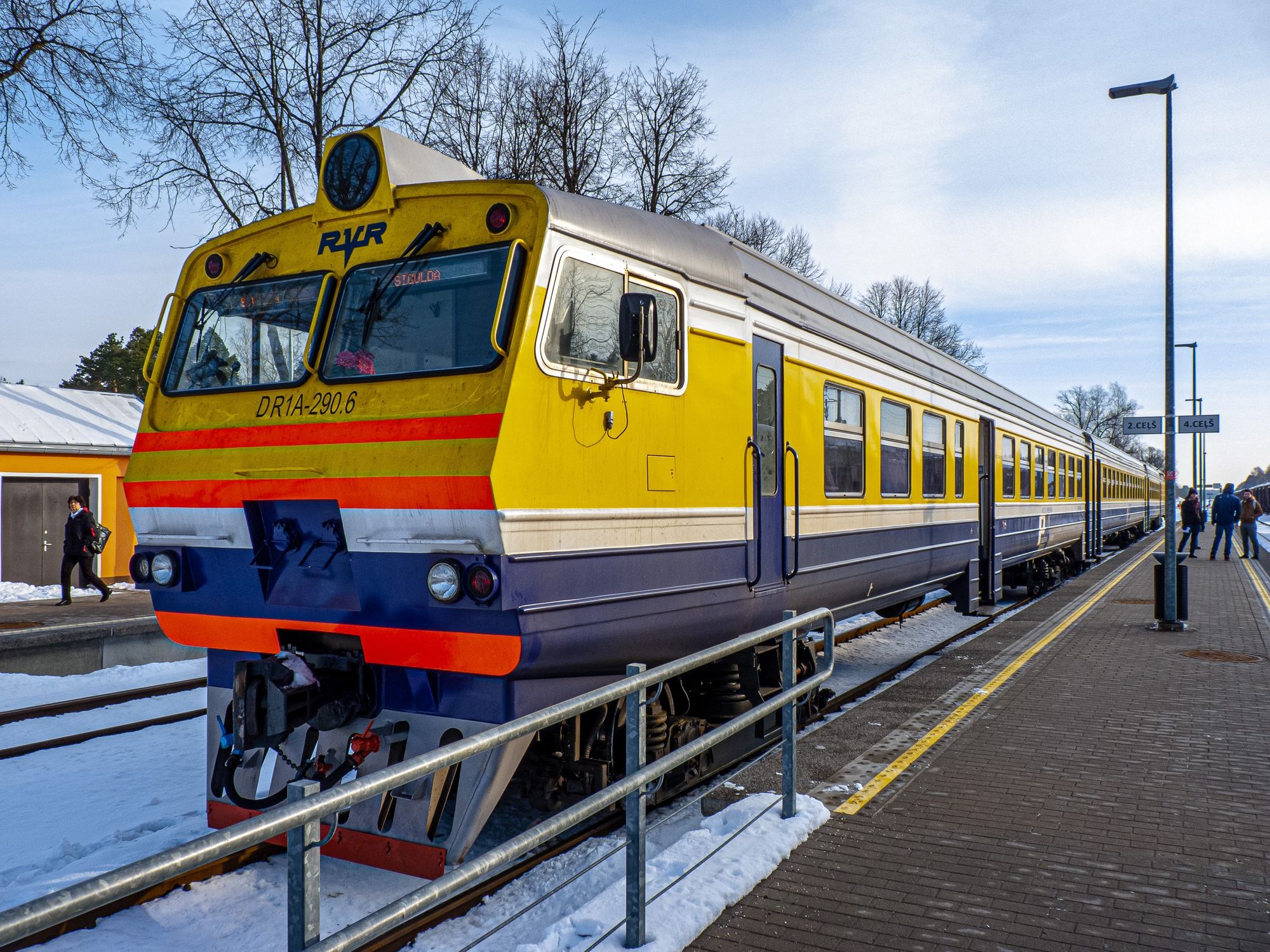 Ein gelb-blauer Triebwagen der lettischen Eisenbahn steht am Bahnsteig im Bahnhof Sigulda