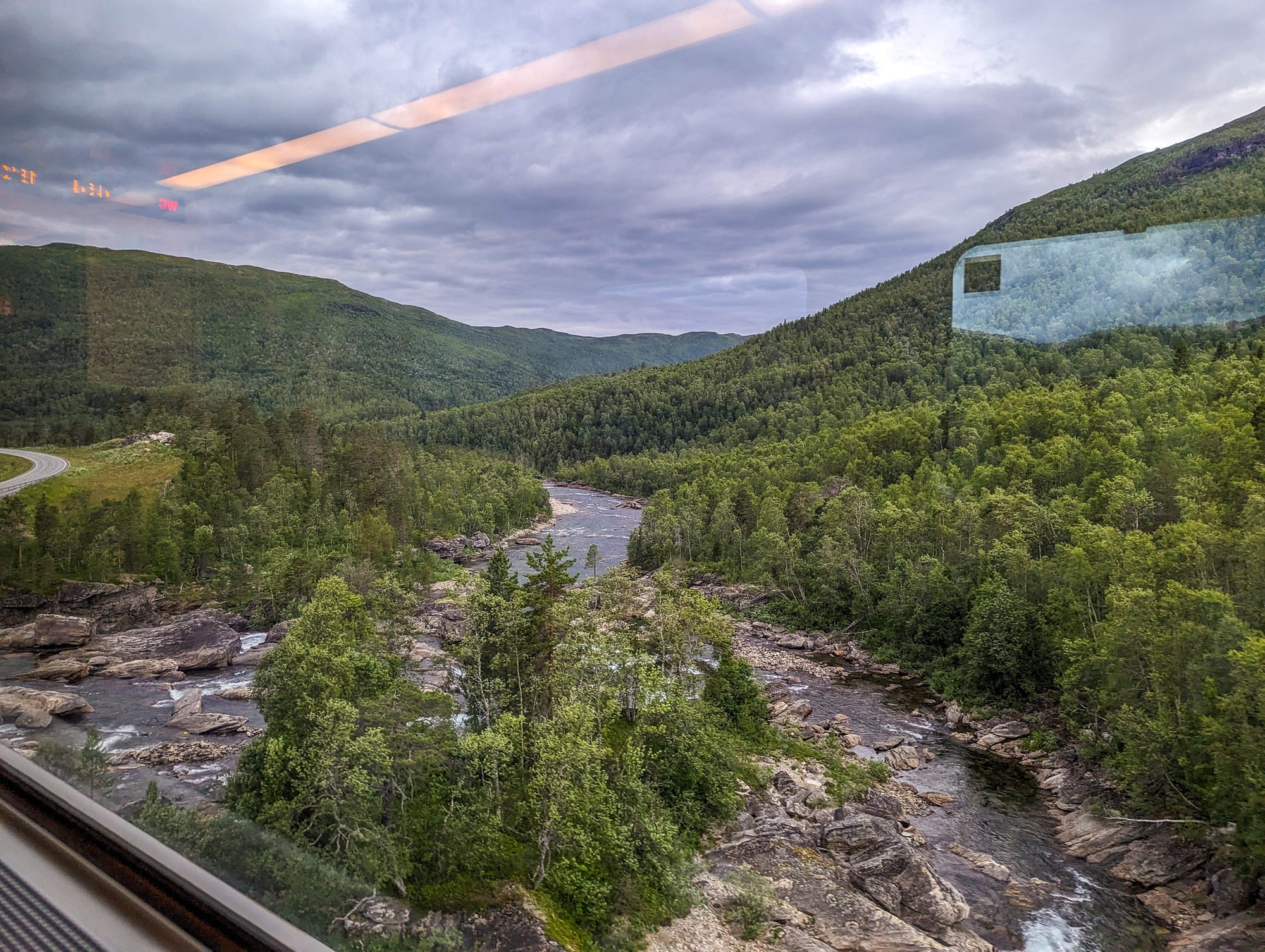 Blick auf dem Zugfenster auf einen reißenden Fluss auf der Nordlandbahn