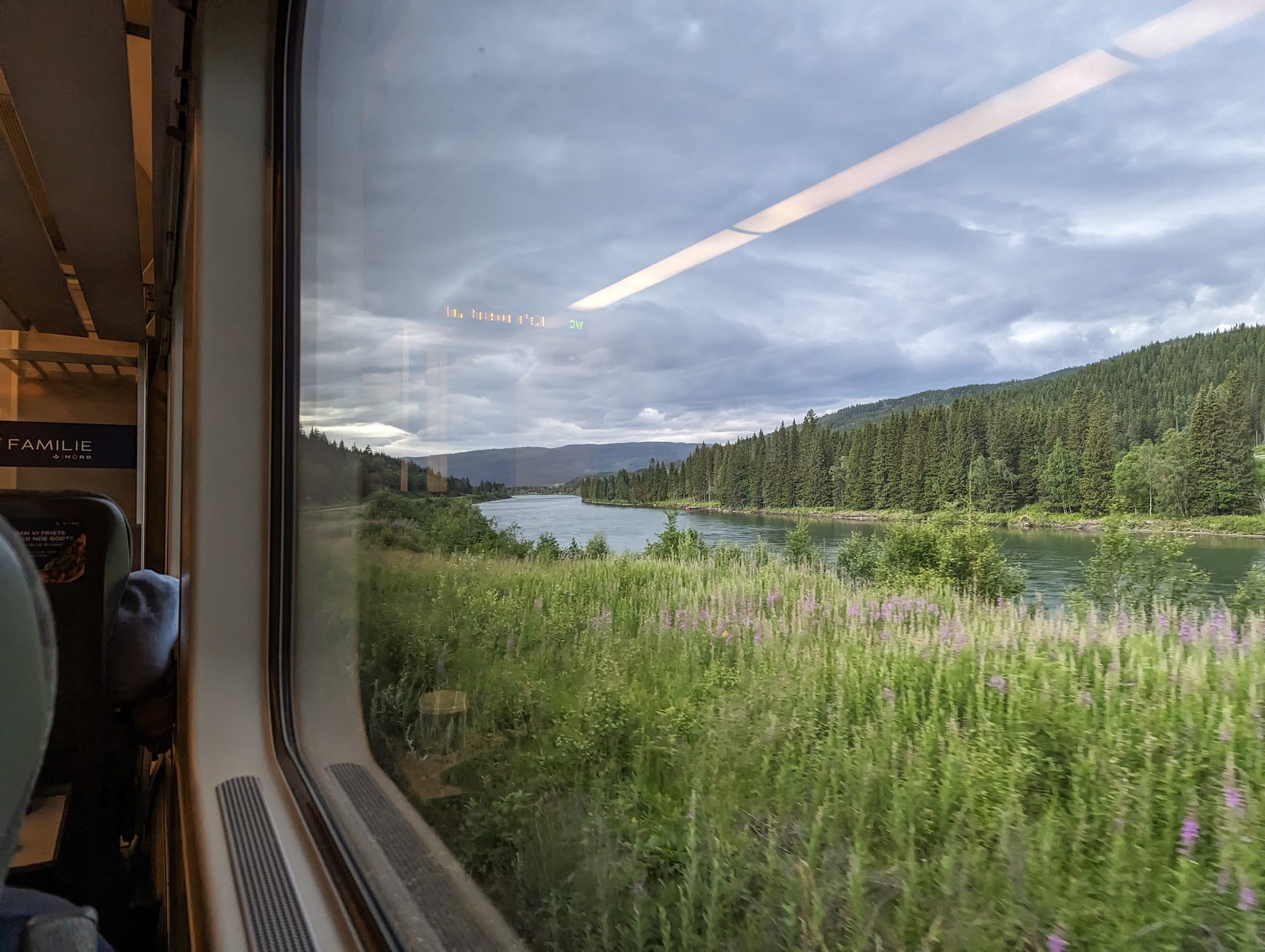 Blick aus dem Fenster auf der Nordlandbahn, eine sommerliche Szenerie an einem Fluss