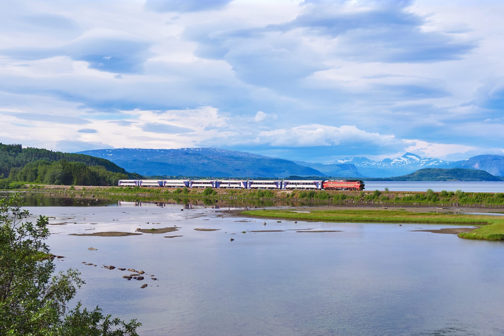Ein Zug auf der Nordlandbahn vor einem Bergpanorama