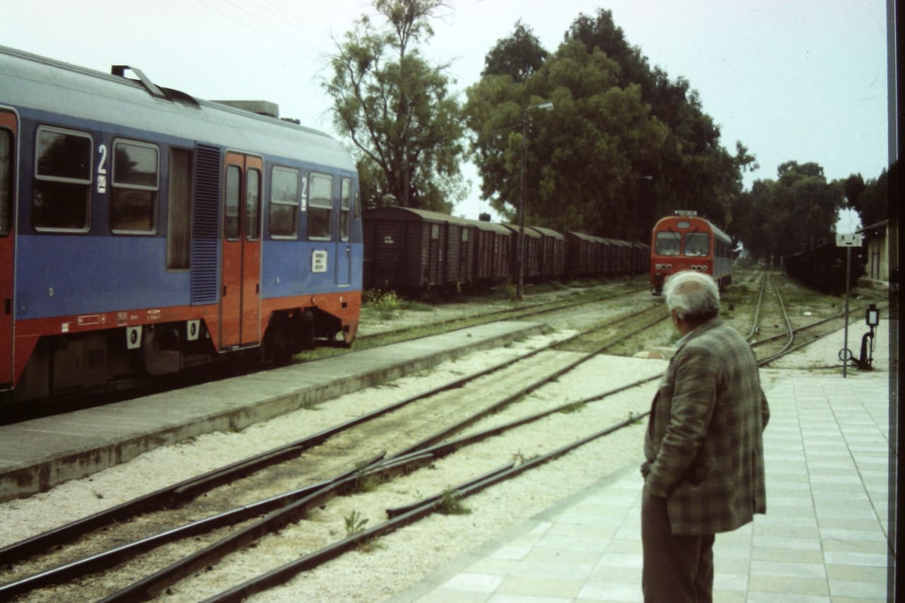 Mann mit kariertem Sakko auf dem Bahnsteig, im Hintergrund Dieseltriebwagen