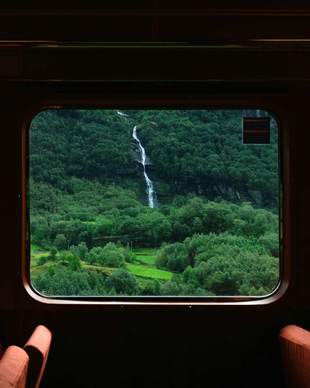 Blick durchs Zugfenster auf einen Wasserfall