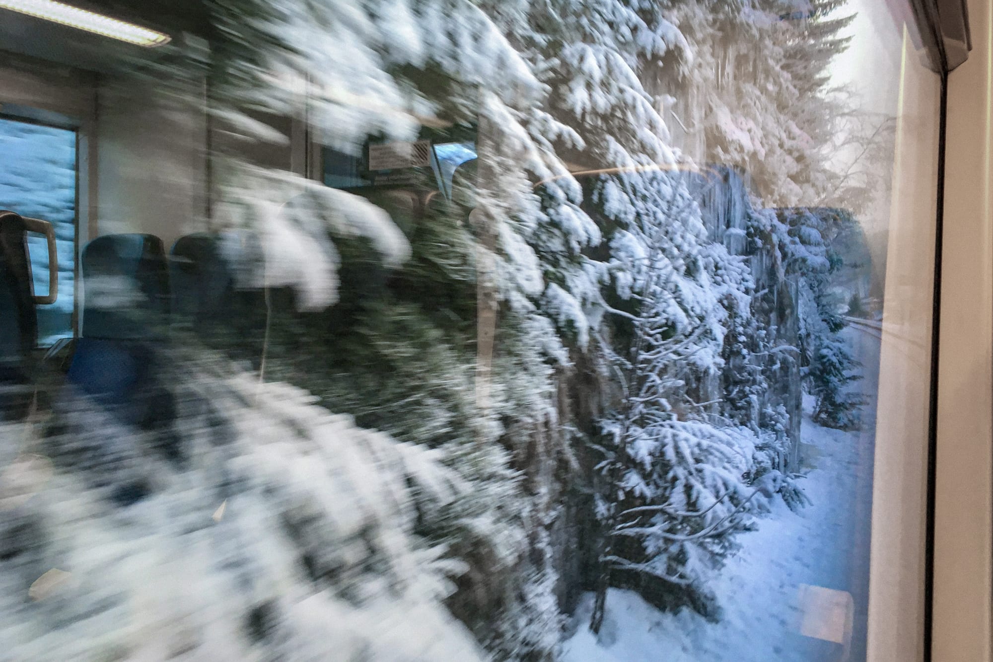 Blick aus dem Zugfenster auf eine Felswand mit Schnee